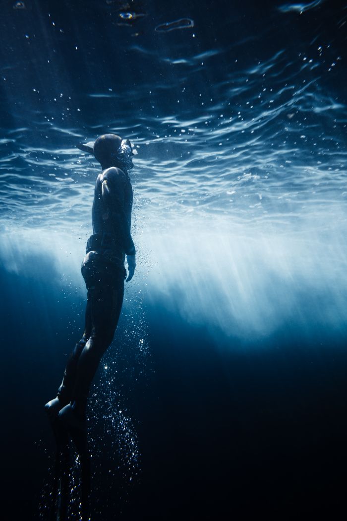 A mesmerizing shot of a freediver ascending towards the sunlit surface of the water, captured underwater.